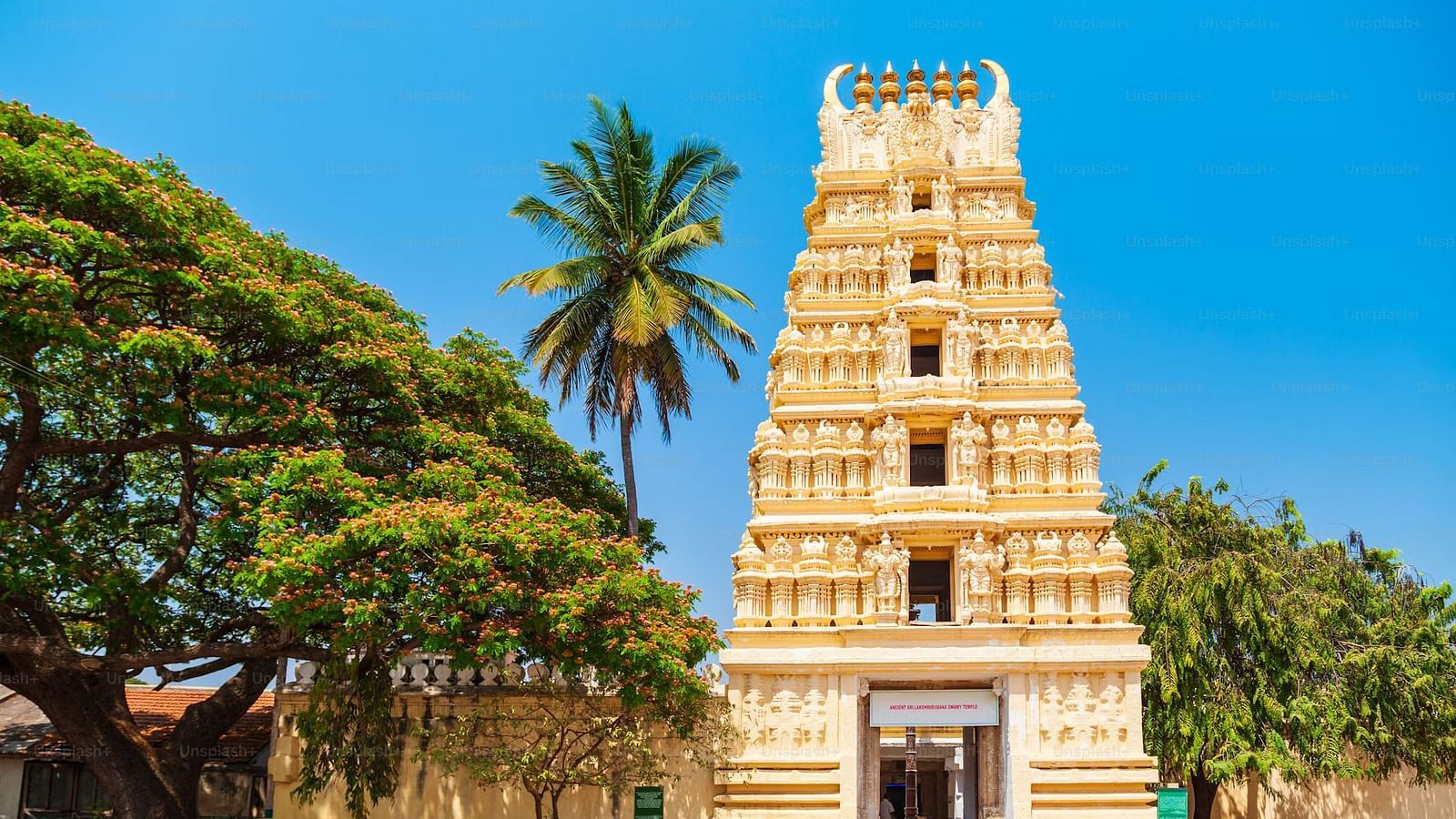 Temple with a towering gopuram, surrounded by palm trees and clear skies.
