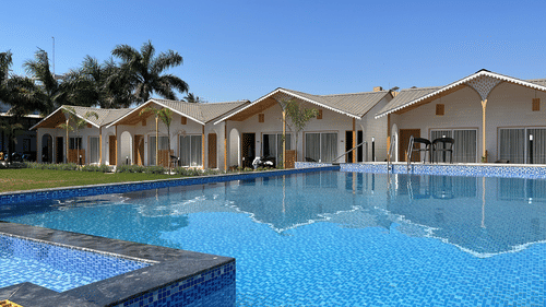 image featuring several bungalows with a huge swimming pool in the foreground - VITS Daman Devka Beach