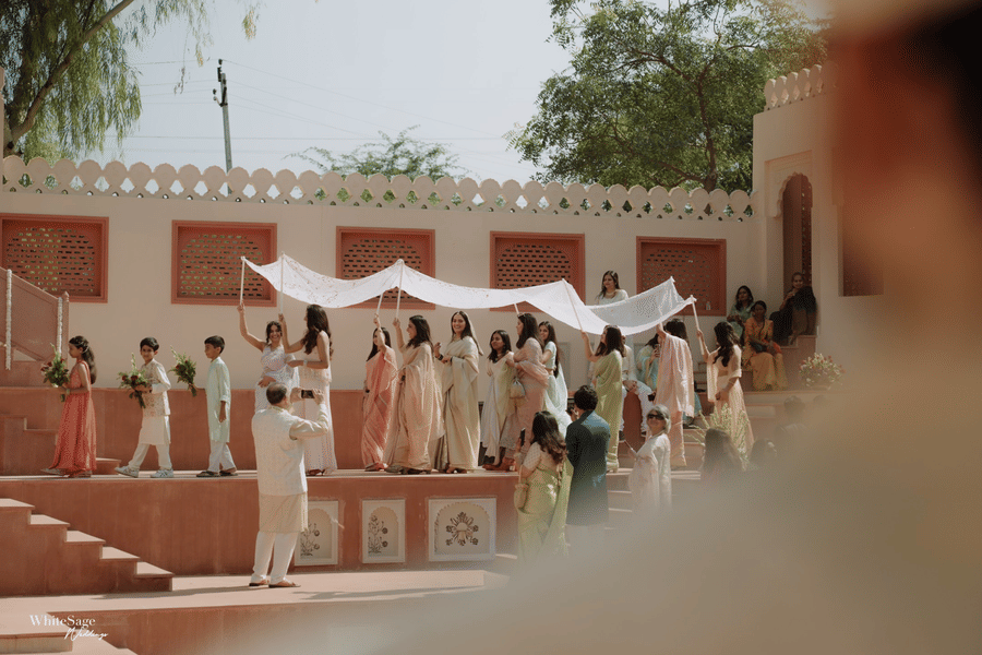 Guests carrying a white canopy over the bride along courtyard stepwell stairs at Umaid Palace.