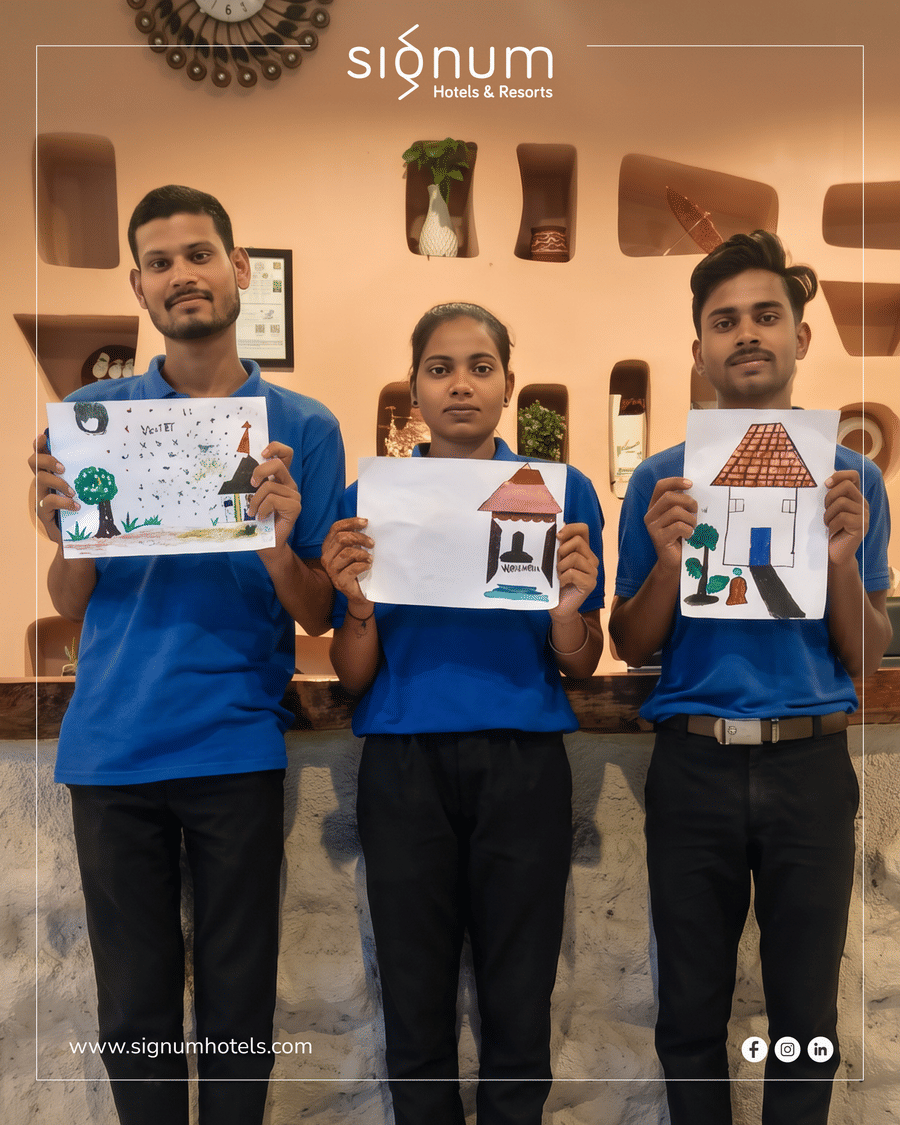 Three Signum Resort team members at reception holding drawings made during a staff engagement activity