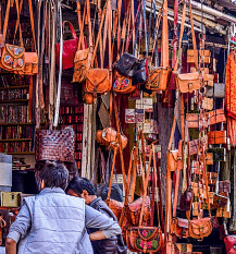 A busy street scene with numerous bags and other goods hanging for sale.
