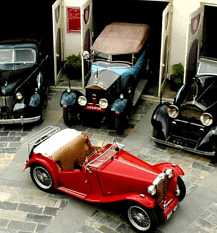 Vintage car collection, including convertible and classic cars, parked in a courtyard.