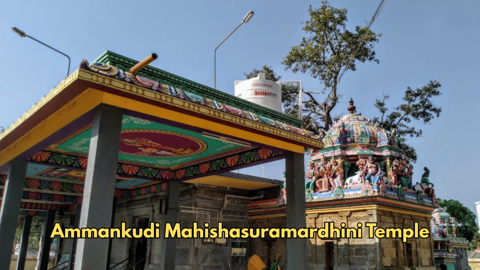 A porch with pillars stands at the entrance of Ammankudi Mahishasuramardini Temple. Shrines rise in the background behind the roofline. 