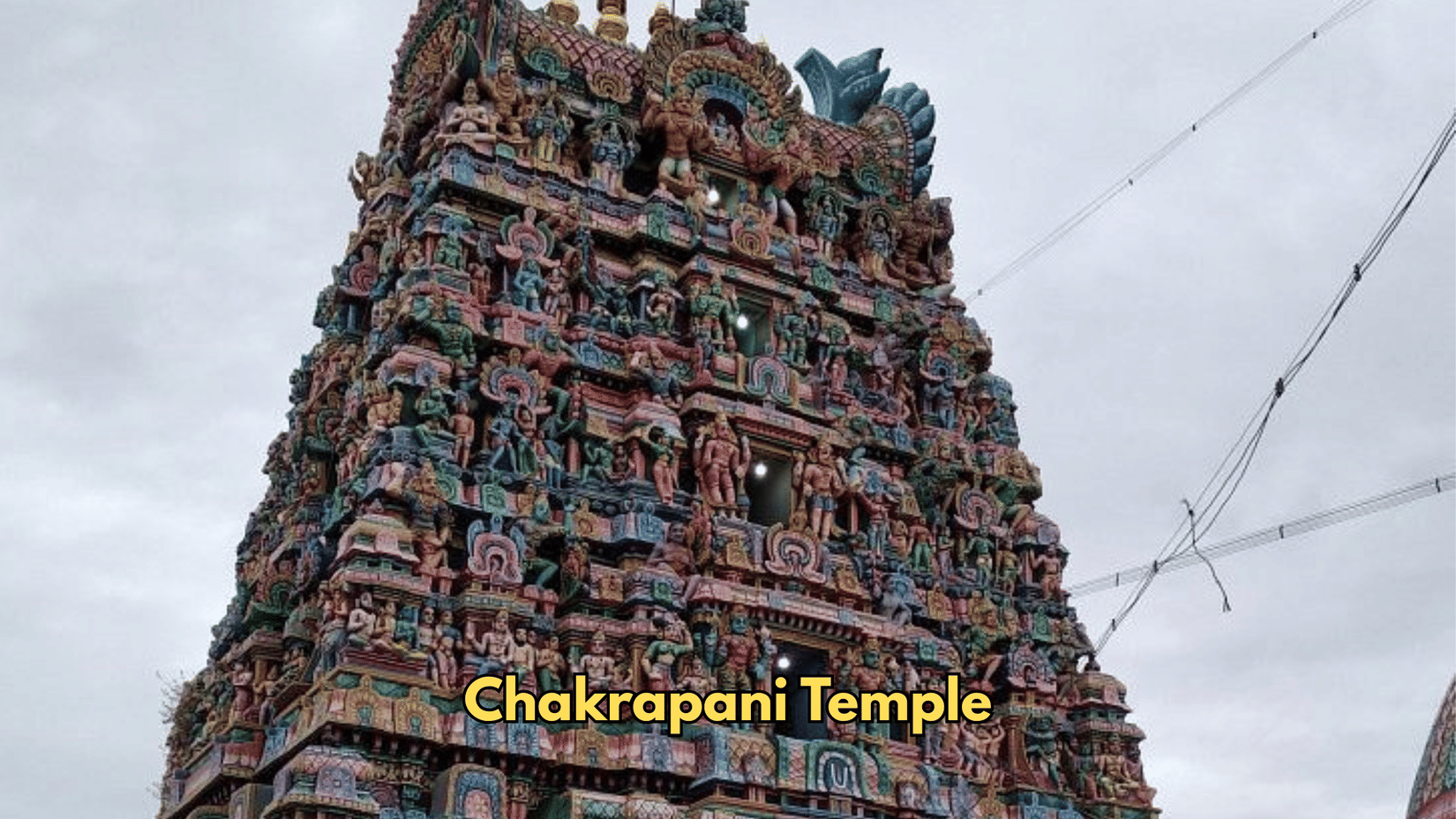 The tower of Chakrapani Temple reaches upward against the sky. Rows of sculptures fill the tiers of the facade.