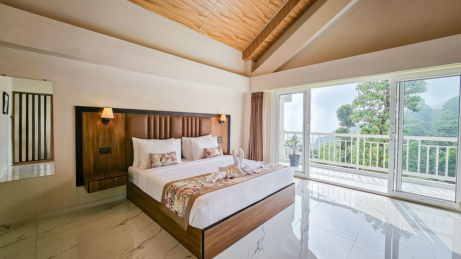  A well-lit bedroom at Yashshree Resort & Spa Kalimpong with a large bed, a wooden headboard, and a balcony offering a view of the outdoors.