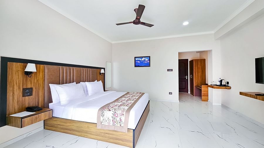 A well-appointed hotel room at Yashshree Resorts & Spa, Kalimpong, featuring two comfortable twin beds, a desk, and a ceiling fan.