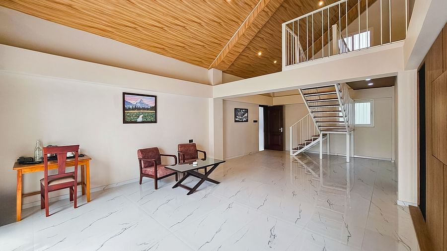 A spacious, open-plan living area with high, sloped wooden ceilings and a seating arrangement, showcasing the interior of Yashshree Resorts & Spa, Kalimpong.
