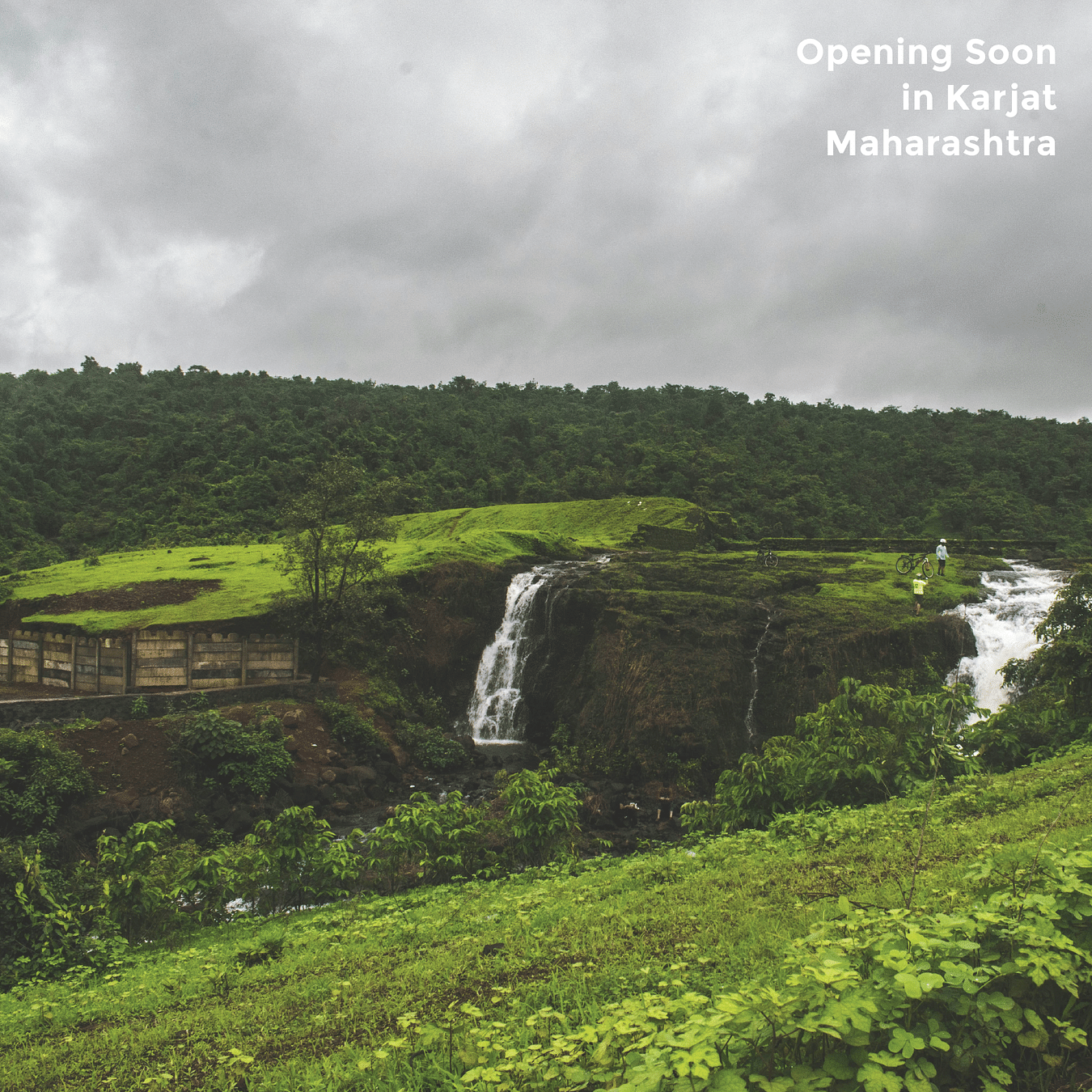 A scenic landscape under an overcast sky features a waterfall cascading down rocks into lush green surroundings with text - Opening Soon in Karjat Maharashtra.