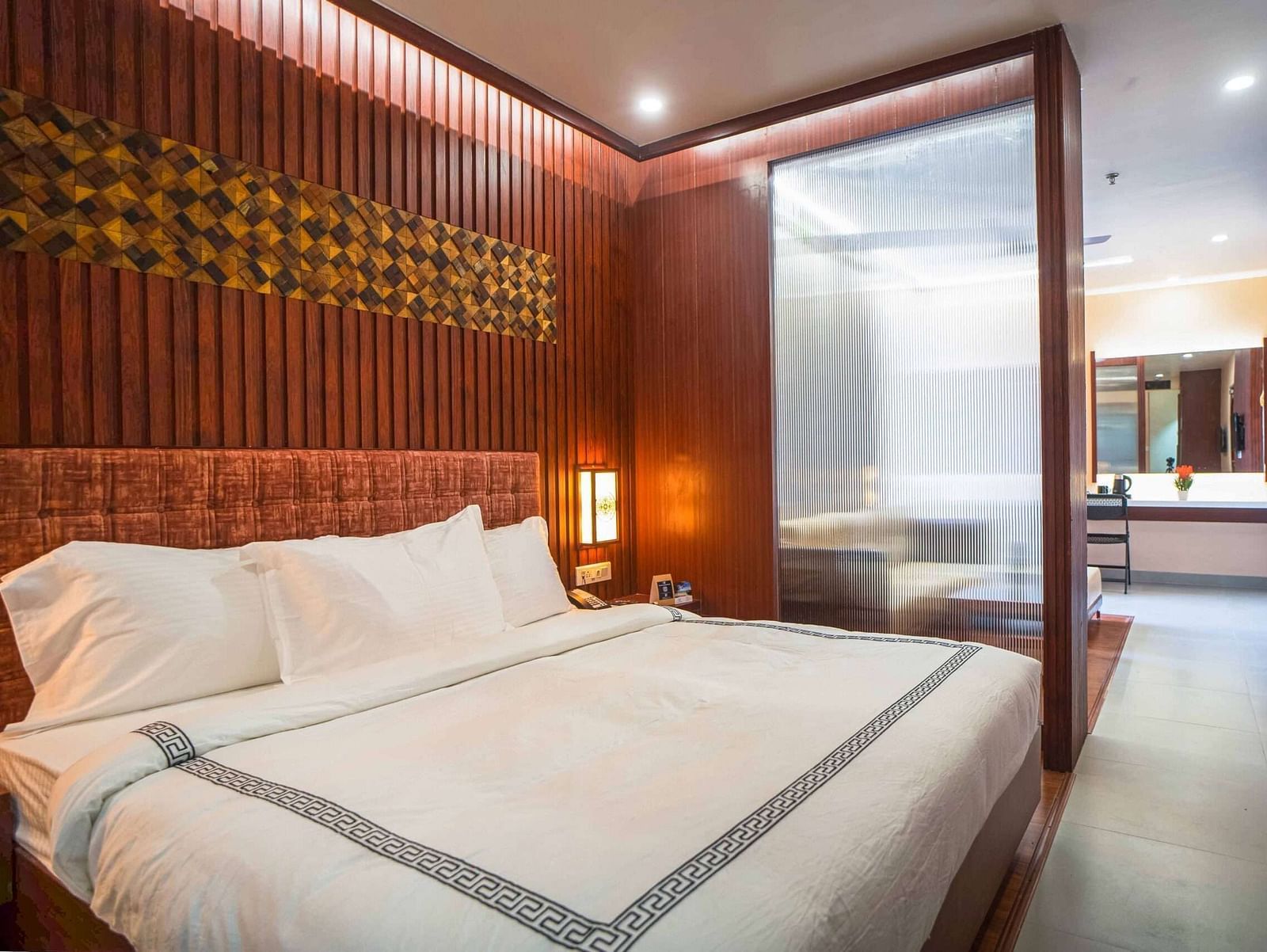 A stylish bedroom at Mansha Palace features a comfortable bed and a partial view into an adjacent area with a desk.