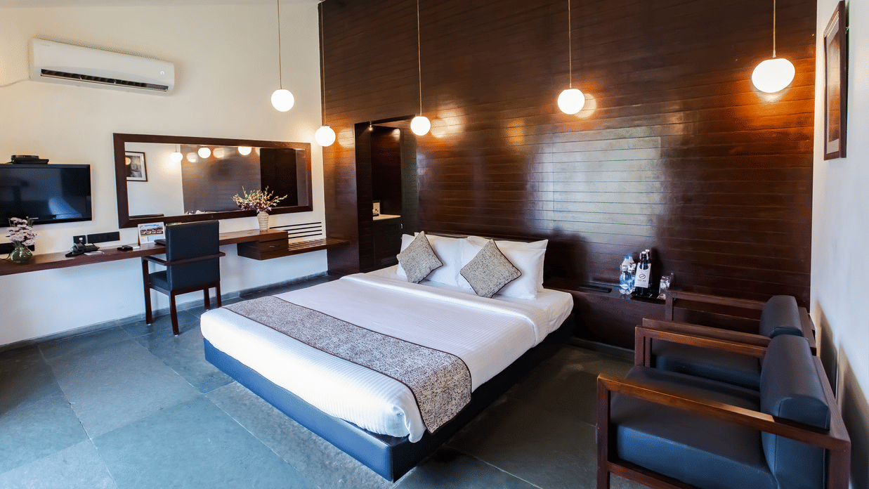 A room at MGM Beach Resorts, with a double bed, spreads, pillows, wall arts, and a sofa.