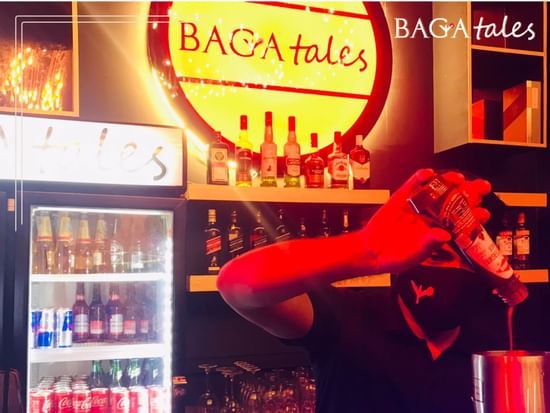 A bartender mixing drinks at the counter, in Baga Tales that has neon lighting | Amara Oceanfront Resort, Baga
