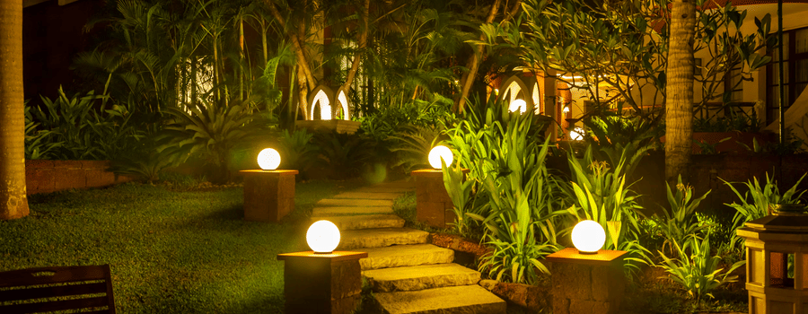 a walkway next to potted plants in caravela beach reasort goa