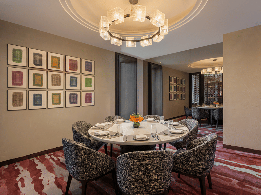 Executive Lounge with a round dining table, framed art wall and chandelier at The Residency Signature Madurai.
