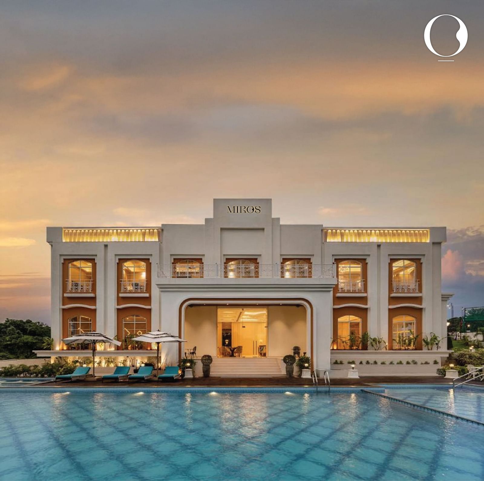 Full view facade of Miros Hotels with a calm swimming pool in the foreground along with beautiful sunset skies in the background.