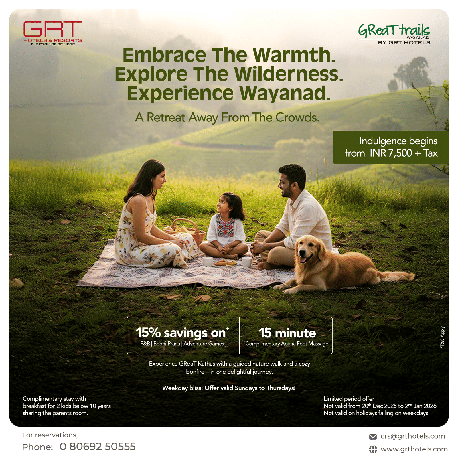 A family enjoying a picnic with their dog in a lush green meadow surrounded by hills during a peaceful weekday stay at GReaT Trails Wayanad by GRT Hotels.