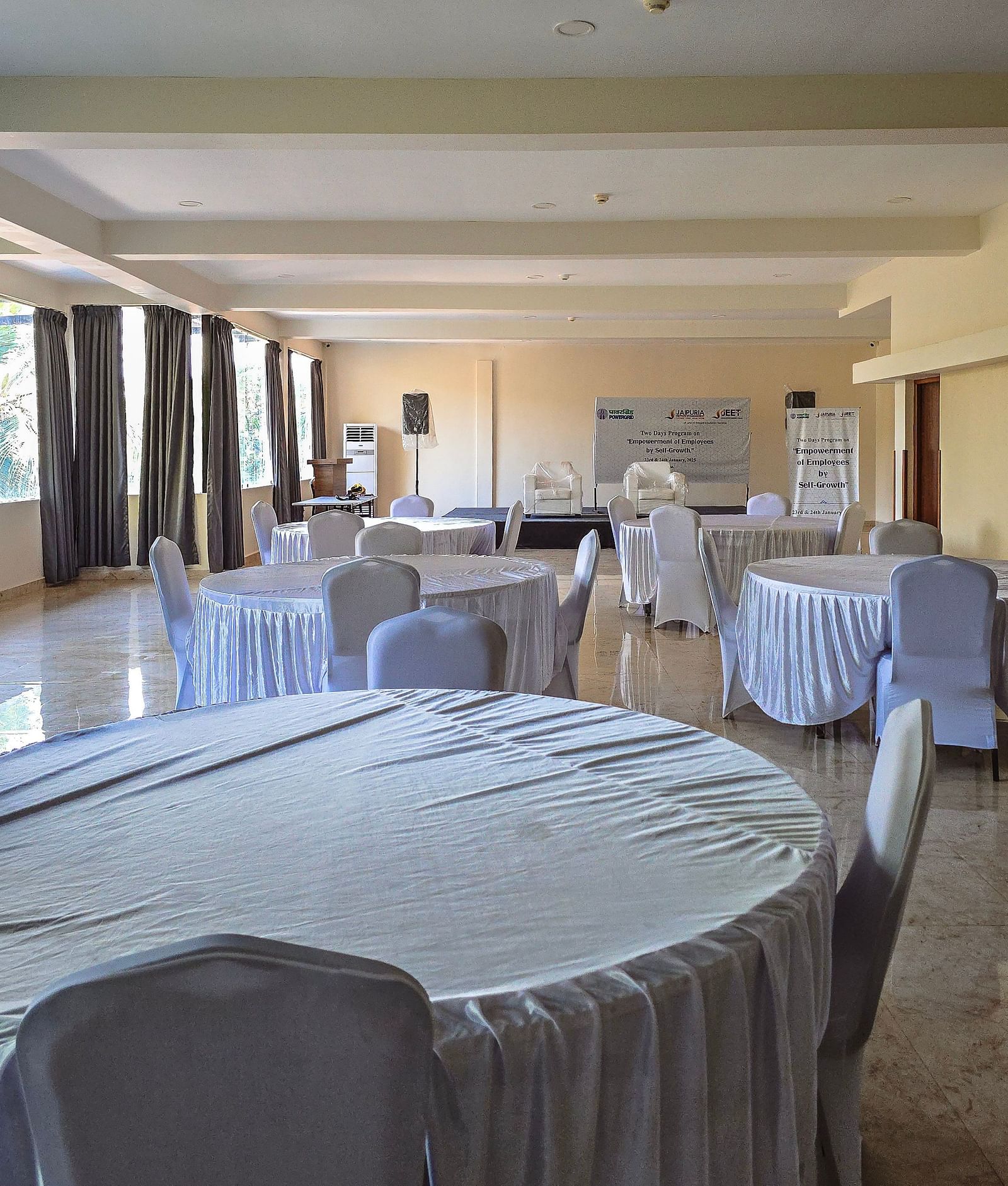 Event space set up with white-covered round tables and natural lighting at The Verda de Miranda Resort.
