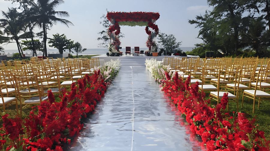 Beachfront wedding ceremony setup featuring a red floral decorated mandap, aisle runner, and guest seating at Kenilworth Resort & Spa, Goa.