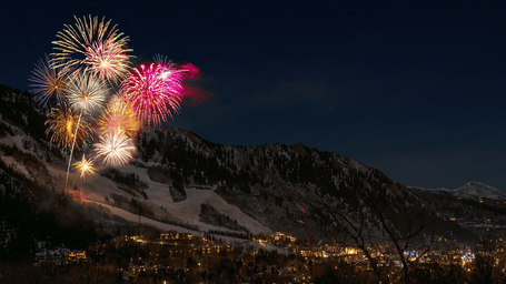 An far out view of fireworks near a mountain side with buildings below it, signifying New Year in Rajasthan.