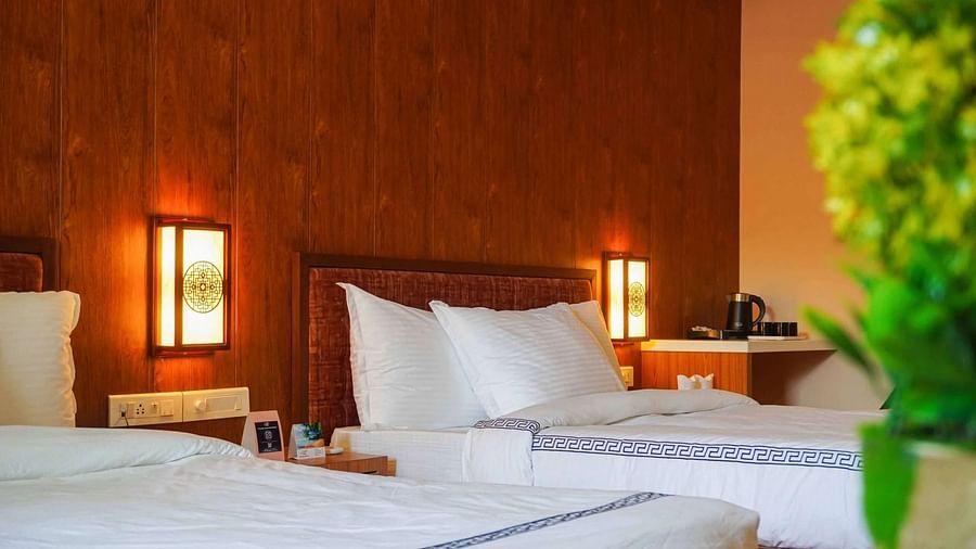 A warmly lit room at Mansha Palace features two comfortable beds and wooden wall accents.