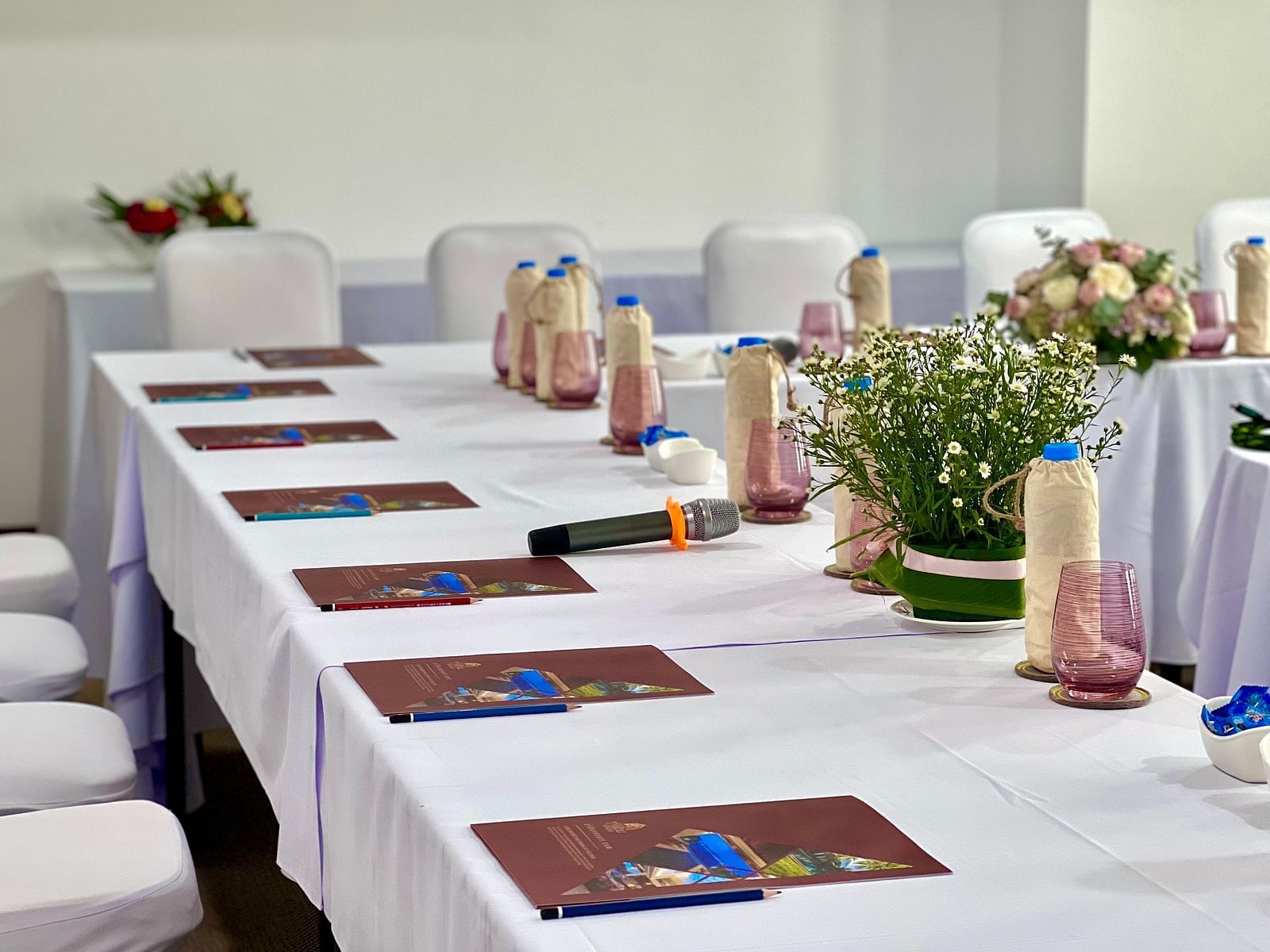 A close up shot of a table with water bottles and wireless mics placed on it - Alibu Resort