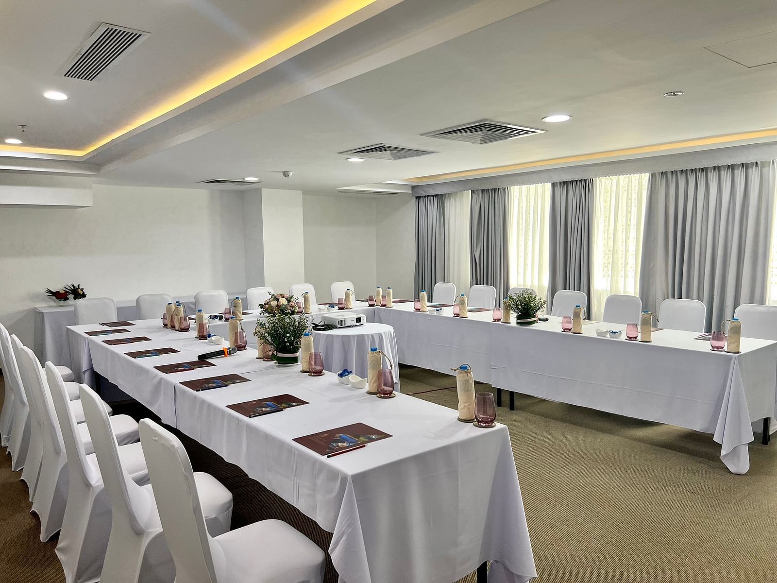 A side angle shot of our meeting room with a u-shaped table and ambient lighting - Alibu Resort
