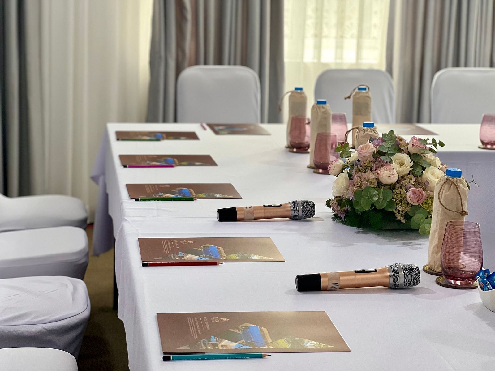 Another angle of a table with water bottles and wireless mics placed on it - Alibu Resort