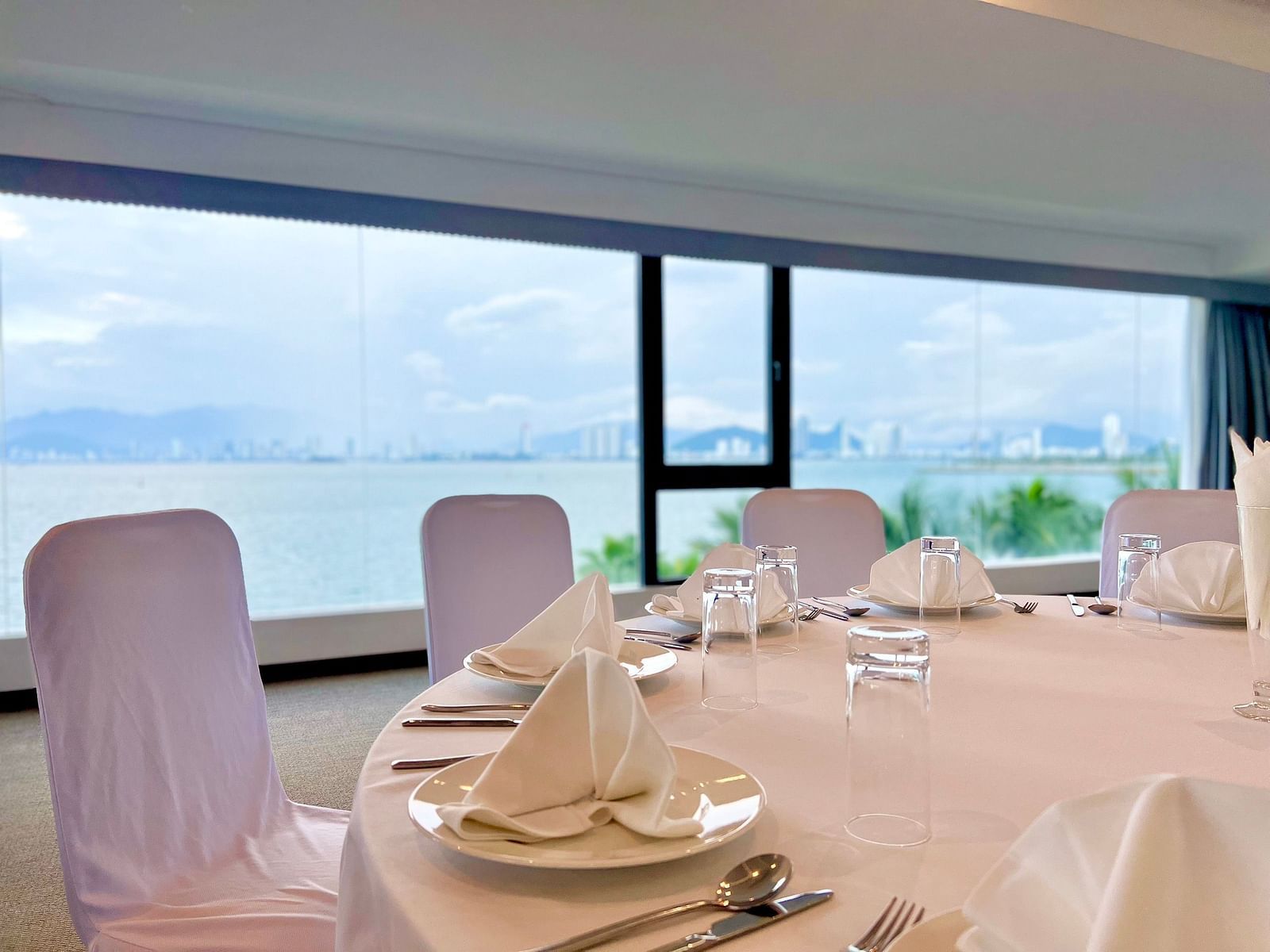 A close up shot of a round table in our meeting hall near a glass window with the view of the Nha Trang Bay - Alibu Resort