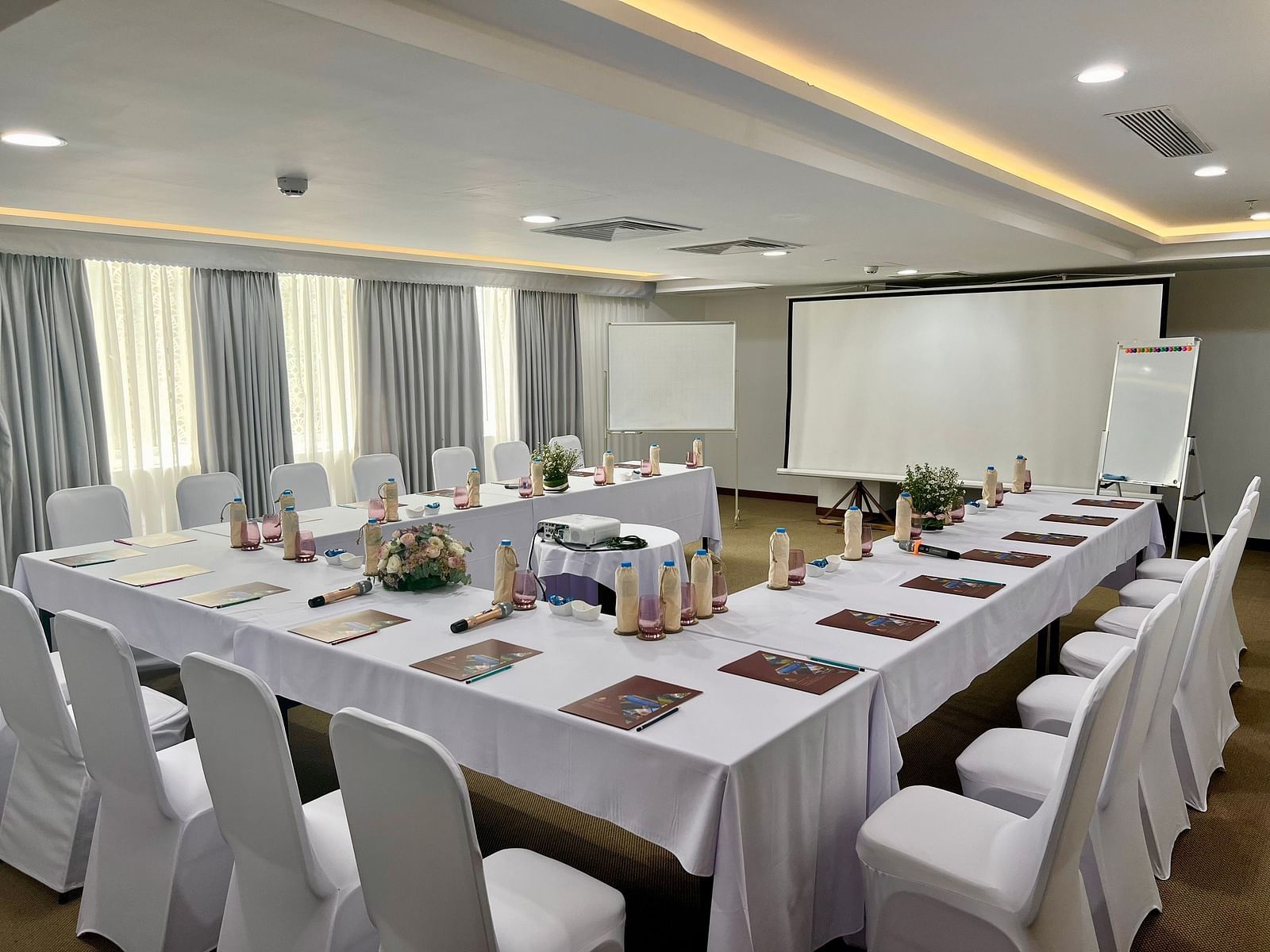 A meeting room with a u-shaped table in front of a projector screen - Alibu Resort