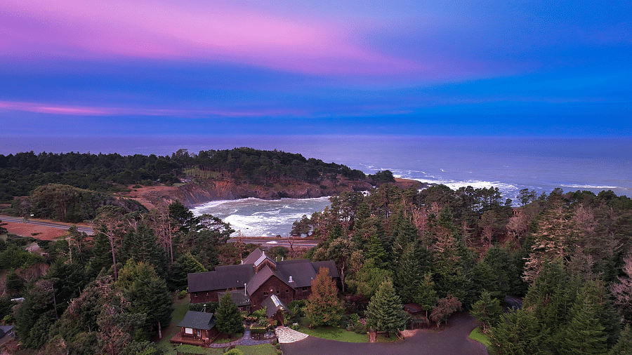 Stunning aerial view of the coastline at sunset, with a vibrant purple and pink sky over the ocean - Brewery Gulch Inn & Spa