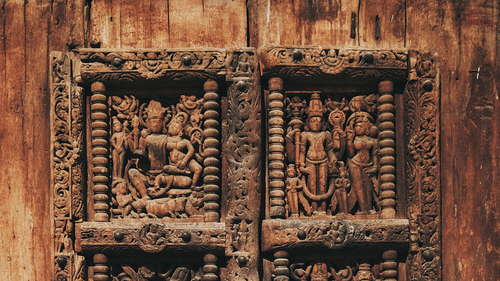 Detailed wooden door with intricate carvings depicting religious figures in traditional craftsmanship.