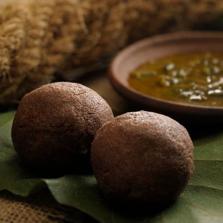 Two Ragi Mudde balls with a bowl of curry.
