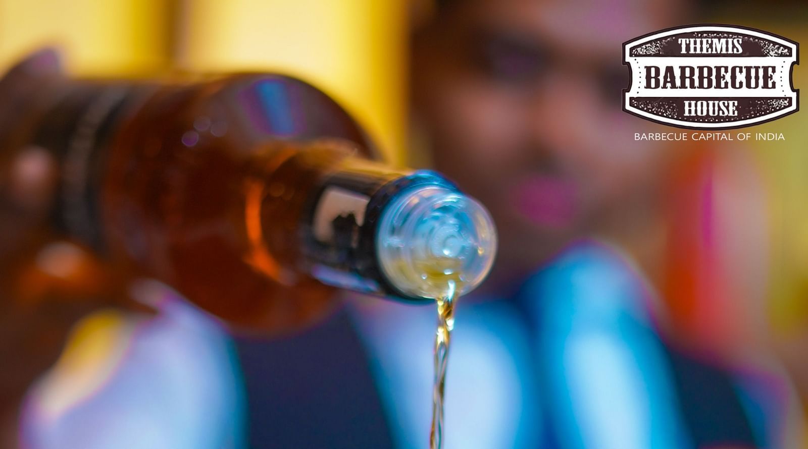 An image of a person pouring drink on a glass at Themis Barbecue House, Panipat