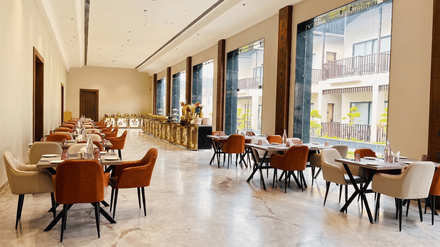 Pride Premier Alwar | A dining space with chairs and tables in a pathway.