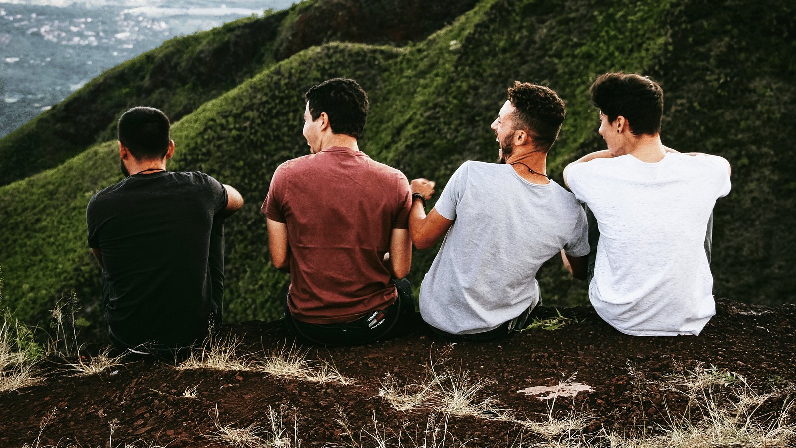 an image of Friends chilling on a hill peak laughing together