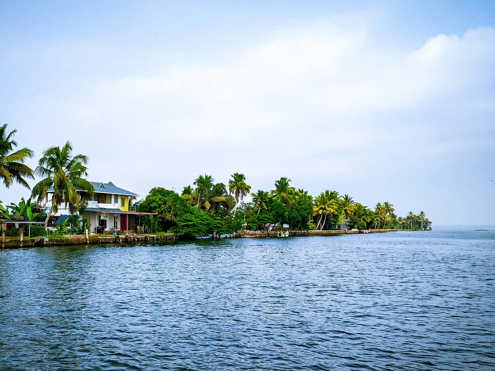 Backwater with a two-storey building on the bank surrounded by trees