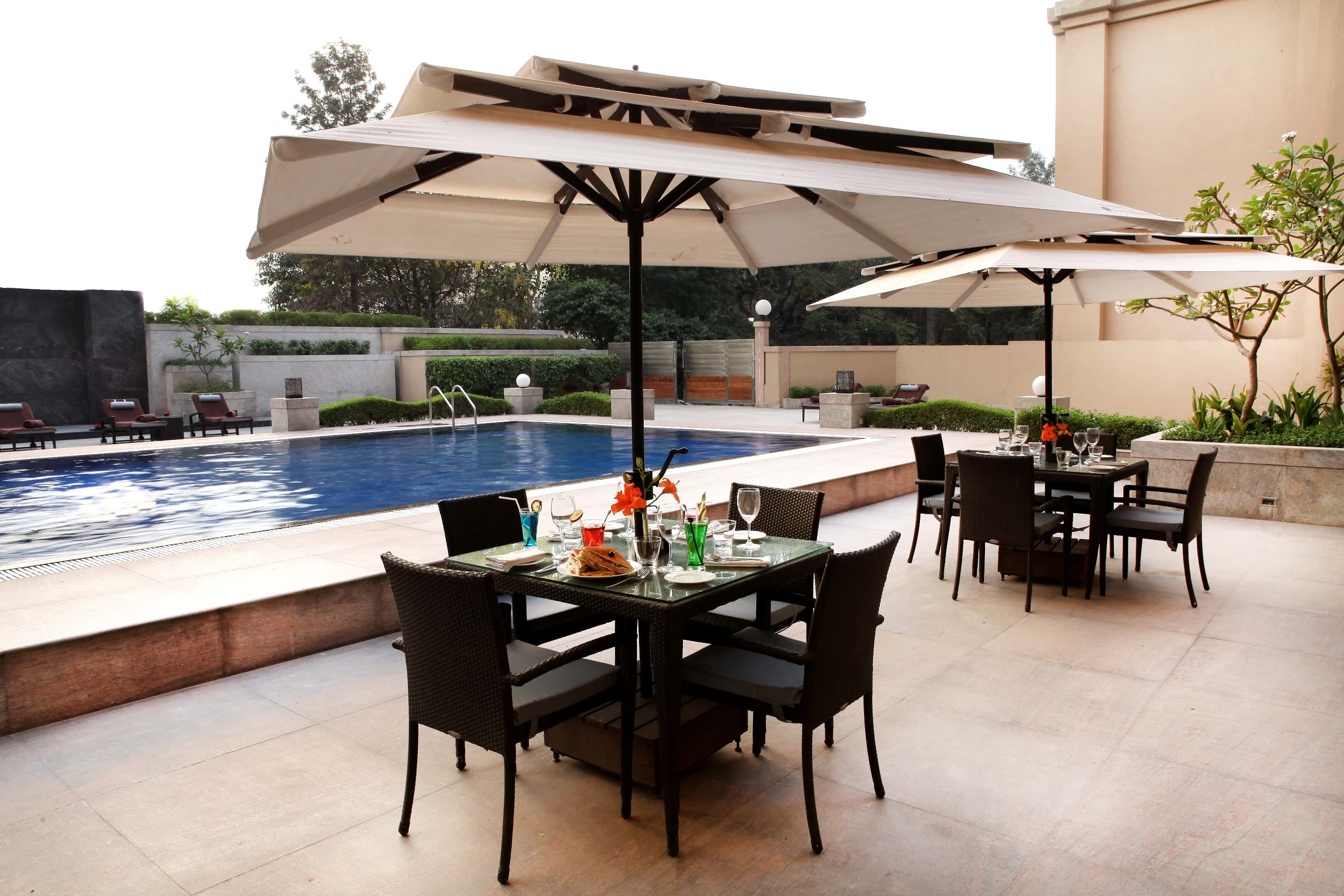 The open-air swimming pool, loungers and shaded tables along its edge