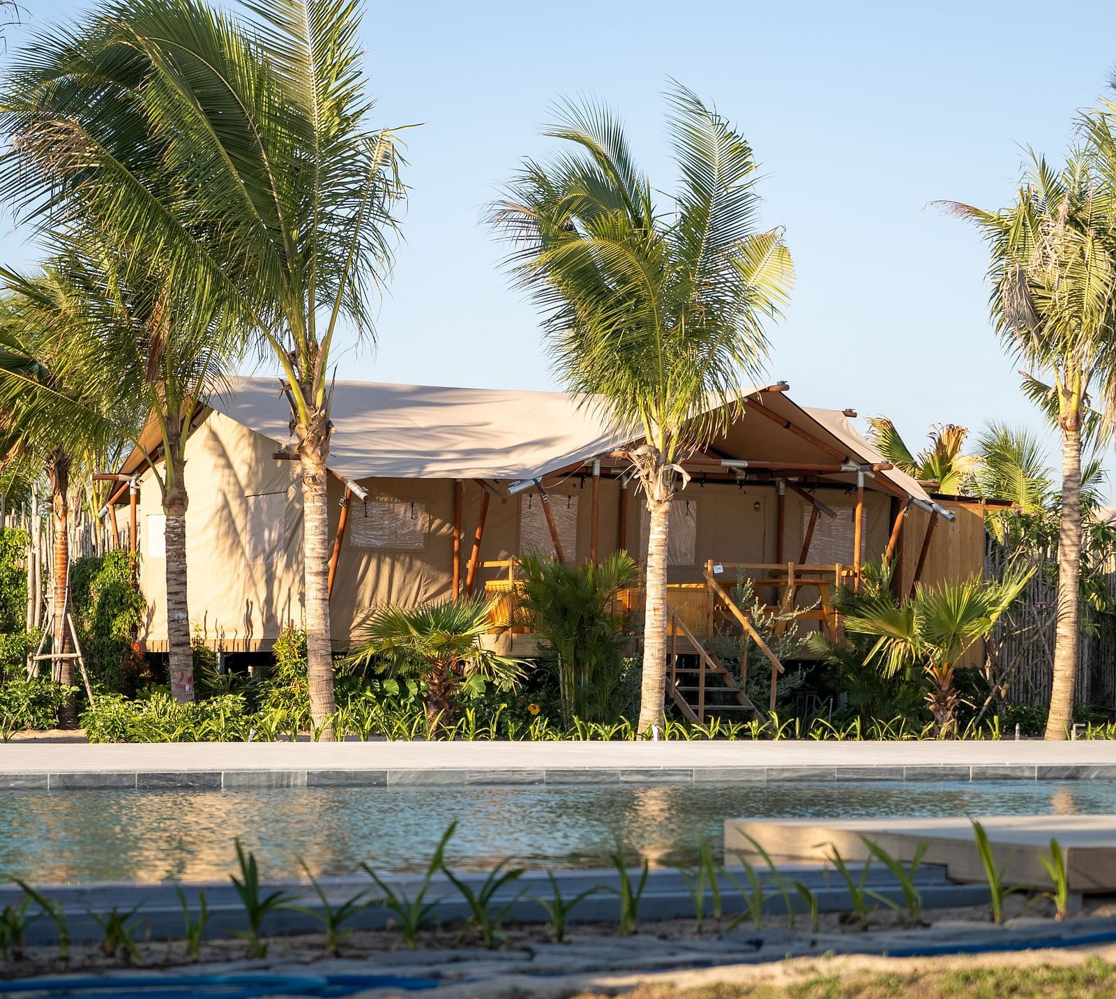 A peaceful poolside setting with tented accommodations surrounded by tropical landscaping at WoCAL Retreat Ke Ga.