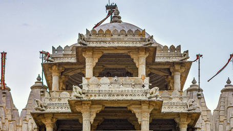 A facade view of Ranakpur Jain Temple in Rajasthan with the steps leading to the temple and railings on either side of the steps.