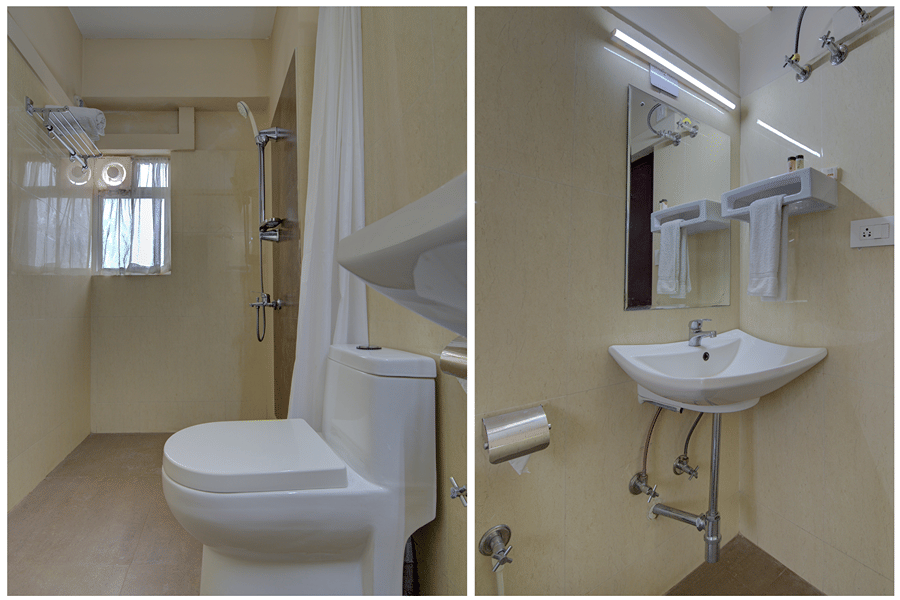 A bathroom at Central Courtyard Boutique Hotel, Siliguri, featuring a toilet nd a sink with mirror above