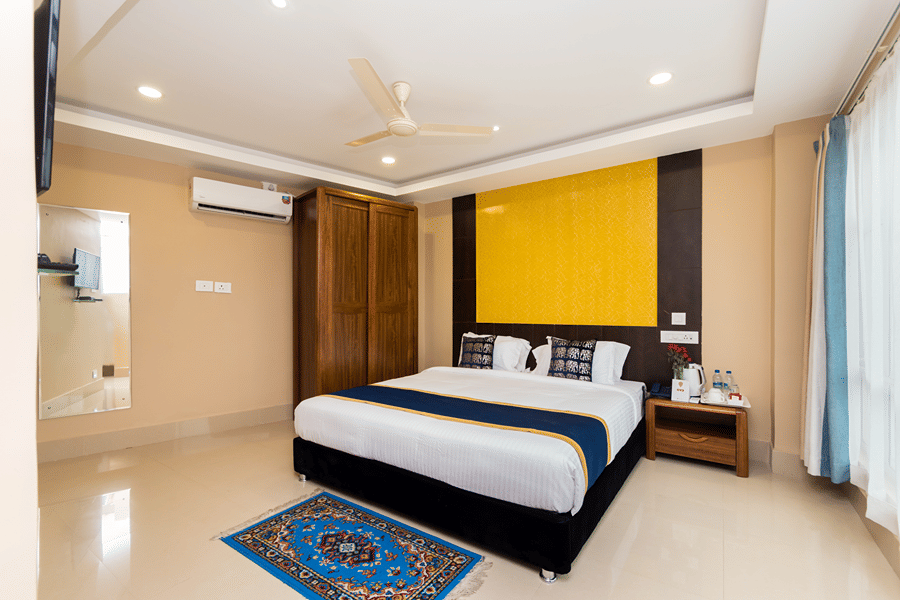 Bedroom of the Suite with Sitting Room at Central Courtyard Boutique Hotel, Siliguri with a plush bed and a carpet at its foot