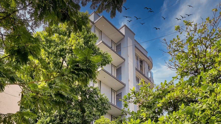 An exterior facade of Home2 Suites & Service Apartments, Mumbai Airport, with trees in the foreground.