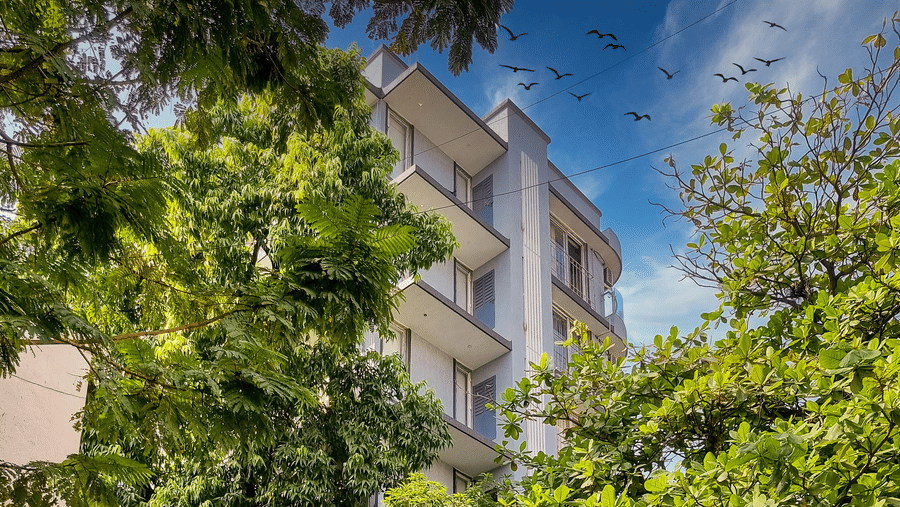 An exterior facade of Home2 Suites & Service Apartments, Mumbai Airport, with trees in the foreground.