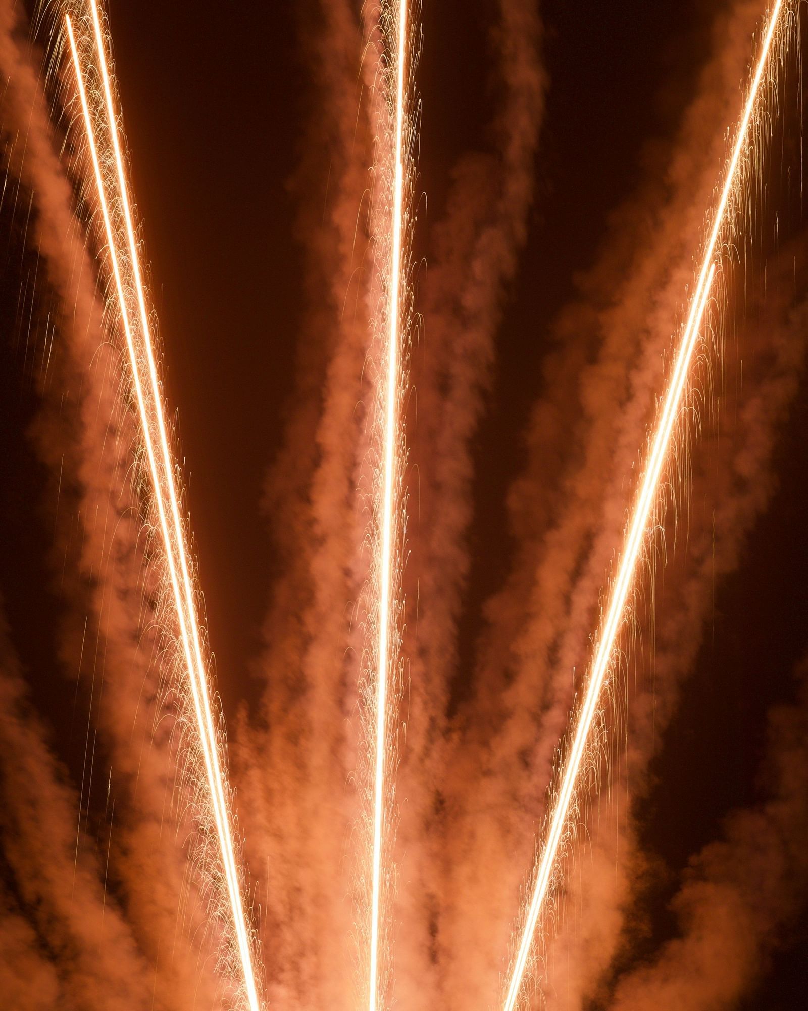 Abstract streaks of warm, glowing light emanate from a dark background.