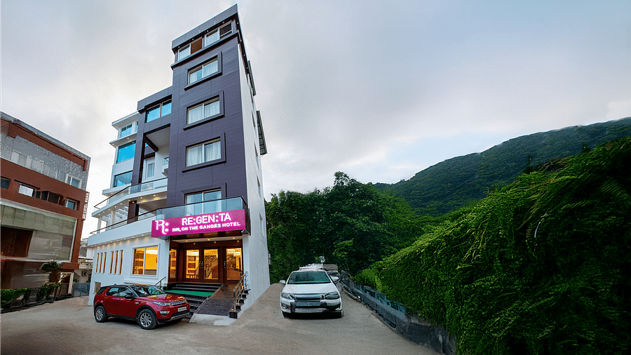 A wind angle shot of Regenta Inn DLS with a lush green hilly region in the background.