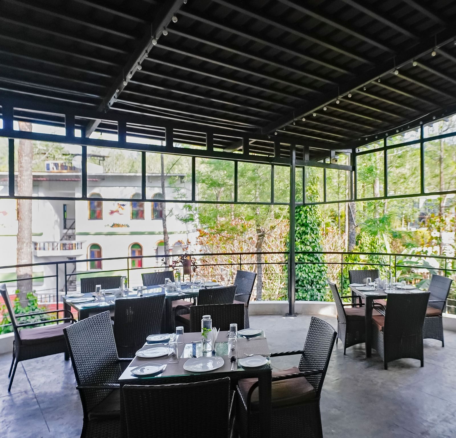 Covered outdoor dining area with tables and chairs neatly arranged at WOW Bungalow, Yercaud. 