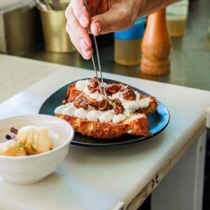Chef garnishing a meat dish with sauce in the kitchen at Tamarind Hills Resort and Villas, Antigua.
