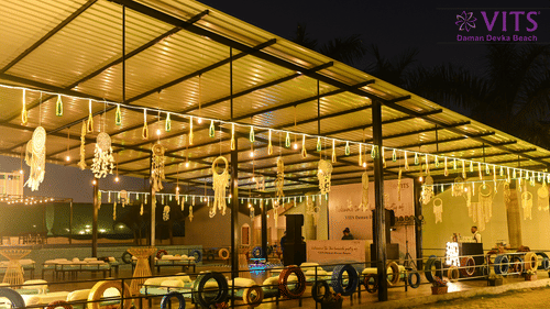 An outside view of Urban Dhaba that can be used as one of the best banquet halls in Daman with LED lights, dream catchers, and seating arrangement in view at VITS Daman Devka Beach.