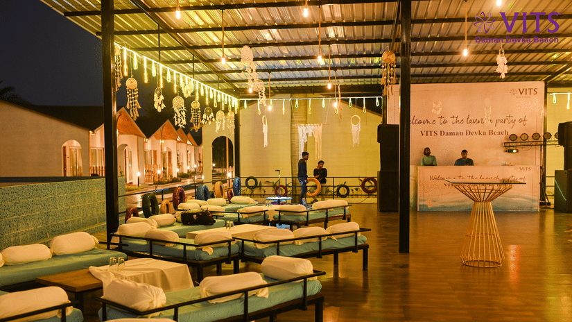 A view of the seating arrangement at Urban Dhaba, the best restaurant in Daman, featuring a reception desk, dream catchers, LED lights and people in view at VITS Daman Devka Beach.