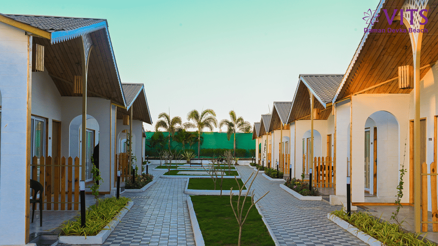 A view of the cobbled walkway with manicured garden in the centre and various accommodations on either side with trees in the distance at VITS Daman Devka Beach - A resort in Daman, near Devka Beach.