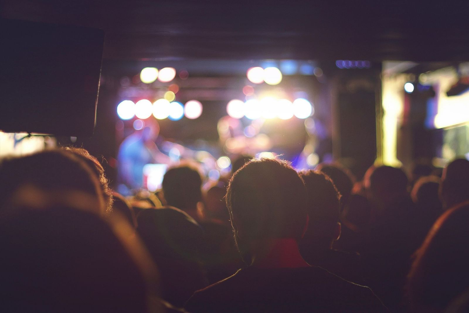 an image crowd in a live concert with illuminating yellow lights. 